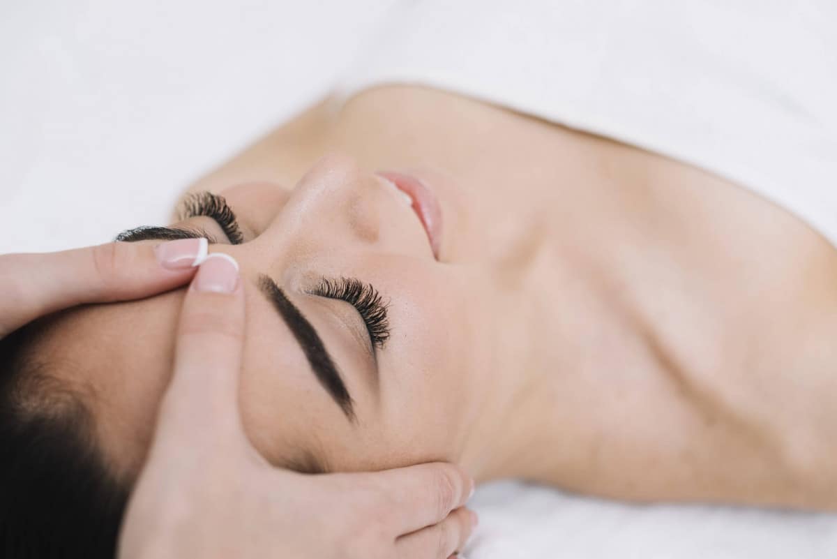 mujer-recibiendo-masaje-facial-relajante-scaled Woman enjoying a relaxing facial massage.